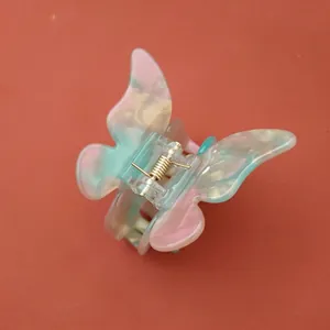 Vue détaillée d'une pince à cheveux papillon aux reflets nacrés roses et verts pastel