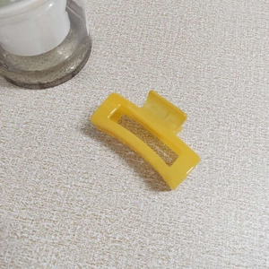 Close-up of bright yellow rectangular claw clip with a glossy finish on light desk