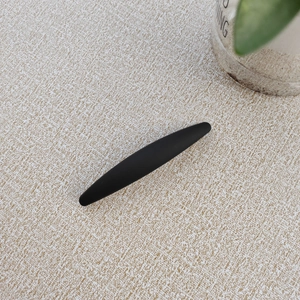 Close-up of minimalist matte black long hair clip with smooth frosted texture on beige fabric