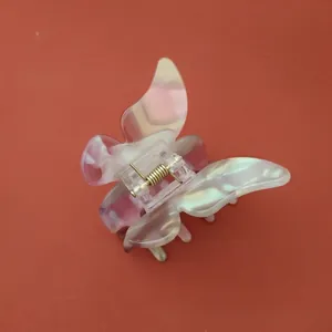 Détail d'une pince à cheveux papillon avec texture marbrée nacrée et ressort doré