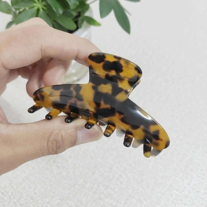 Dettaglio di una grande pinza per capelli in acetato con motivo tartarugato tenuta in mano