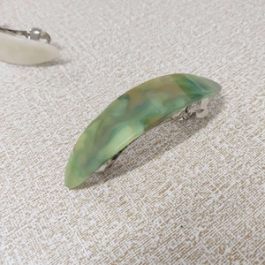 Macro detail of French marble pattern hair clip with green acetate finish and metal spring