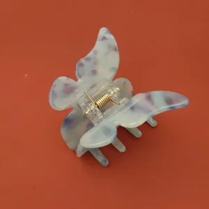 Détail d'une pince à cheveux papillon avec motifs violets en acétate et ressort doré