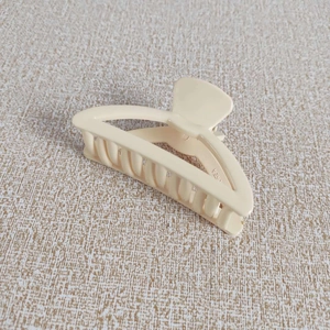 Vue détaillée de la pince à cheveux beige mâte avec design arqué ajouré et dents solides
