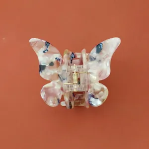Détail de la pince à cheveux papillon avec motif marbré et ressort en métal doré