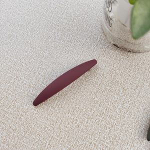 Detailed close-up of a matte burgundy Morandi spring hair clip on a textured background