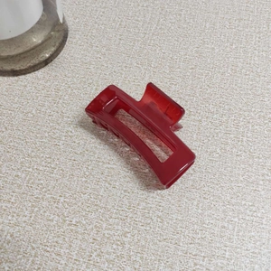 Top view of a translucent burgundy rectangular hair claw clip with internal teeth