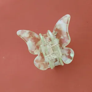 Détail macro d'une pince à cheveux papillon avec texture acétate marbrée vert clair