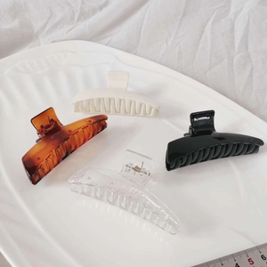 Detail showing four assorted colors of large acrylic hair claws on a white tray