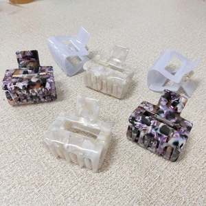 Detailed macro view of square hair claws in lavender, pearl beige and marble textures