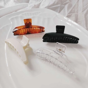 French minimalist acrylic hair claws in amber, black, cream, and clear on a shell tray