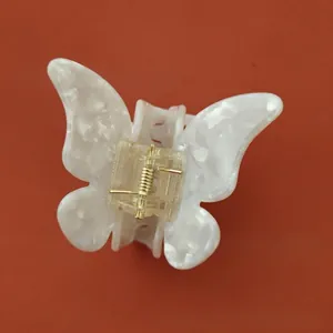 Détail de la pince à cheveux papillon en acétate blanc perle avec ressort doré