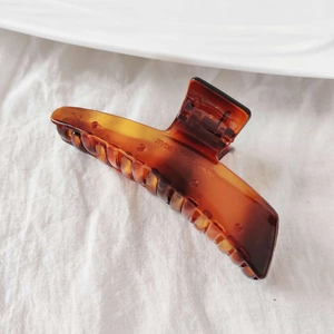 Detailed view of amber acrylic hair claw clip with sturdy metal spring mechanism