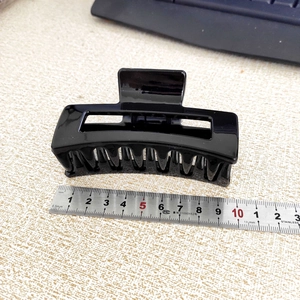 Detail view of large black square hair claw clip measuring 8.5cm with ruler reference