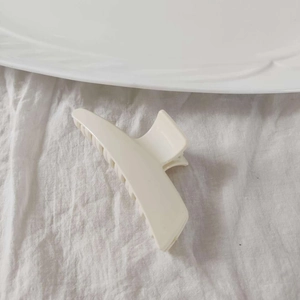 Detail view of cream matte acrylic hair claw clip with crescent moon design on fabric