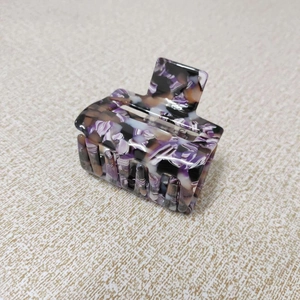 Detail view of square hair claw clip with purple and black marble acetate texture