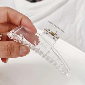 Detail of transparent acrylic hair claw clip with golden metal spring and S84P engraving