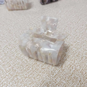 Macro detail of elegant ivory marble hair claw clip with a polished finish