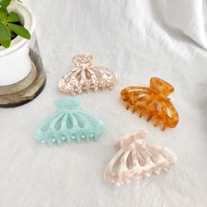 Set of four 9cm acetate hair claws in pastel marble colors on white linen fabric