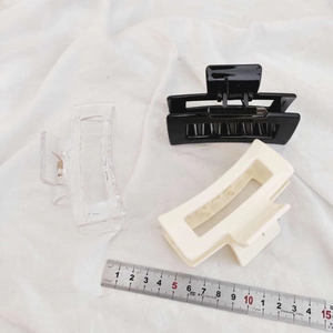Three large square hair claws in black, cream, and clear colors on white fabric