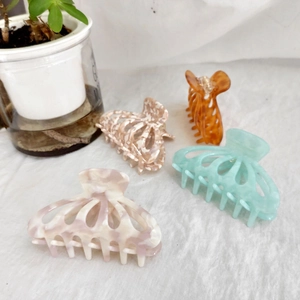 Detail view of 9cm acetate hair claws in pink, beige floral, amber, and light green shades