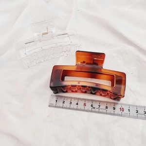 Detail view showing 9cm clear and tortoise shell hair claws on a white textured fabric