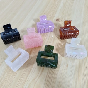 Detailed set of seven colorful square acetate hair claws on a light wood background