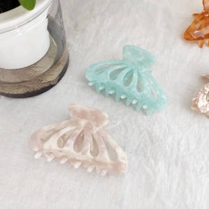 Close-up of marble pattern acetate hair claws in mint green and soft pink colors