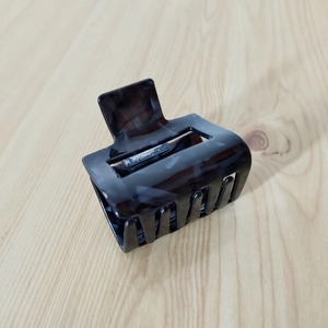 Detailed view of brown acetate hair claw clip with strong metal spring for daily use