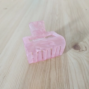 Detail of pink marble acetate hair claw clip with square design on wood surface
