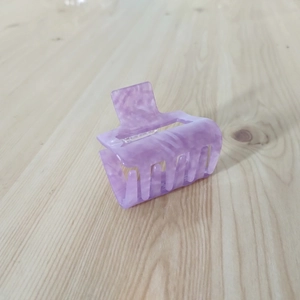 Detail view of purple marble acetate hair claw clip with silver spring on wood
