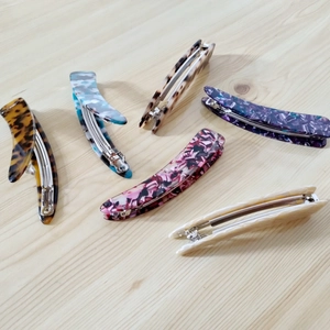 Set of six irregular acetate hair clips with leopard and marble patterns on wood