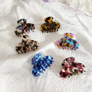 Lot de six pinces à cheveux colorées en acétate aux motifs variés sur tissu blanc