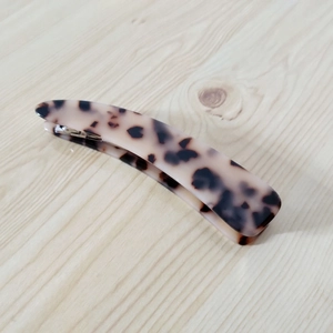 Detailed close-up showing the tortoiseshell pattern and curved resin design of this hair clip