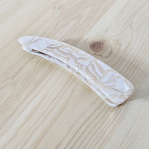Close-up of a marbled acetate banana hair clip with minimalist irregular curved design