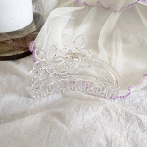 Détail de la pince à cheveux en acrylique transparent avec décorations florales fines