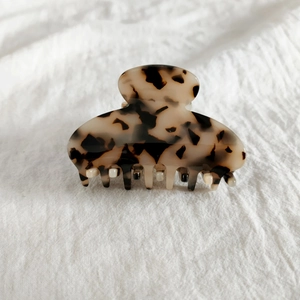 Détail d'une pince à cheveux en acétate écaille de tortue sur fond en lin blanc doux