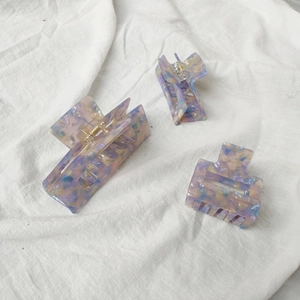 Set of three marble acetate hair claws in purple and blue with gold springs on white fabric