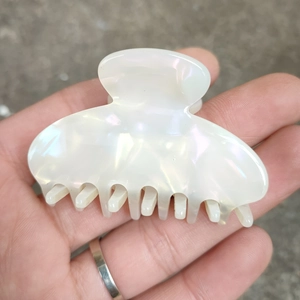 Détail de la grande pince à cheveux blanc nacré avec une finition brillante et élégante