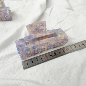 Detailed macro view showing a 10.5cm pink marble acetate hair claw clip on white fabric