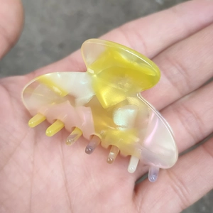 Détail d'une pince à cheveux en acétate à motif marbré avec finition nacrée en main