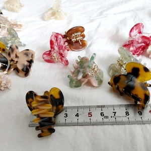 Detail shot of mini acetate butterfly hair clips in various patterns with scale measurement