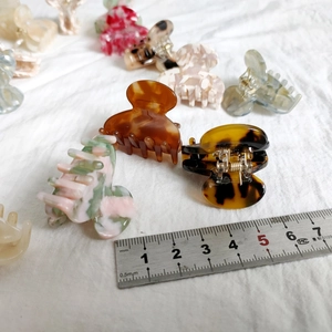 Detailed macro view of assorted leopard and marble acetate hair claws on linen fabric