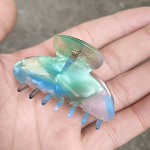 Détail de la pince à cheveux en acétate avec dégradé aurore et design de nuage irisé