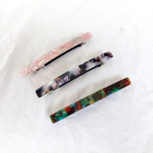 Detailed macro view of 8.5cm acetate spring hair clips with marble patterns on linen fabric