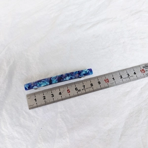 Detail view of 8.5cm blue acetate hair clip with marble pattern on a ruler scale