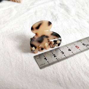 Close-up of 4cm small tortoiseshell hair claw clip with leopard pattern on white fabric