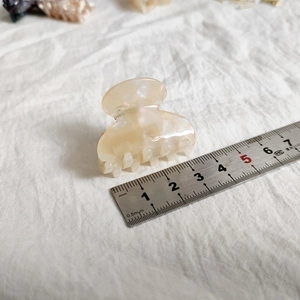 Detailed macro view showing a 4.5cm cream resin hair claw clip with a pearlescent finish