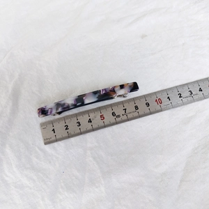 Macro shot of a 10.5cm acetate hair clip with purple marble pattern on a metal ruler