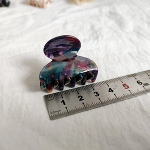 Detail view of a 4cm small marbled acetate hair claw clip with colorful purple and cyan swirls